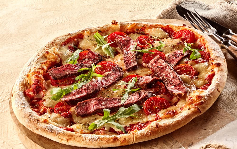 pizza topped with steak and basil