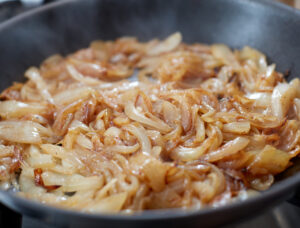 frying mushrooms and onions in pan for cheesesteak recipe