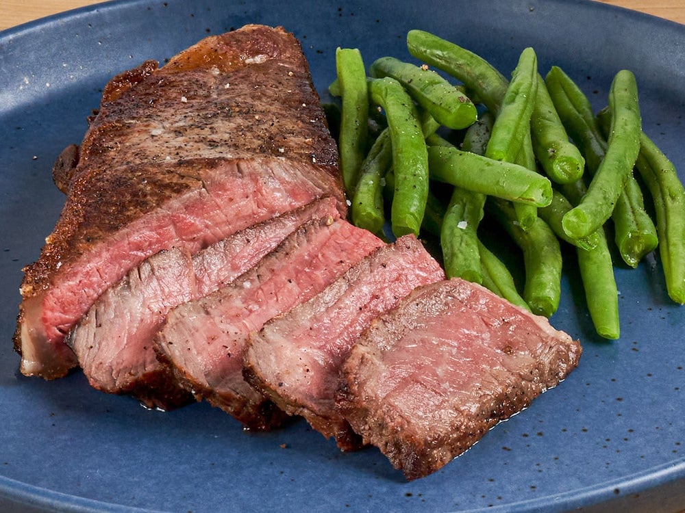 steak with green beans on a blue plate